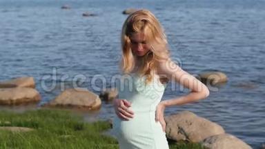 海滩上的<strong>孕妇</strong>。 妻子一个穿着蓝色裙子的<strong>孕妇</strong>站在大海的背景上。